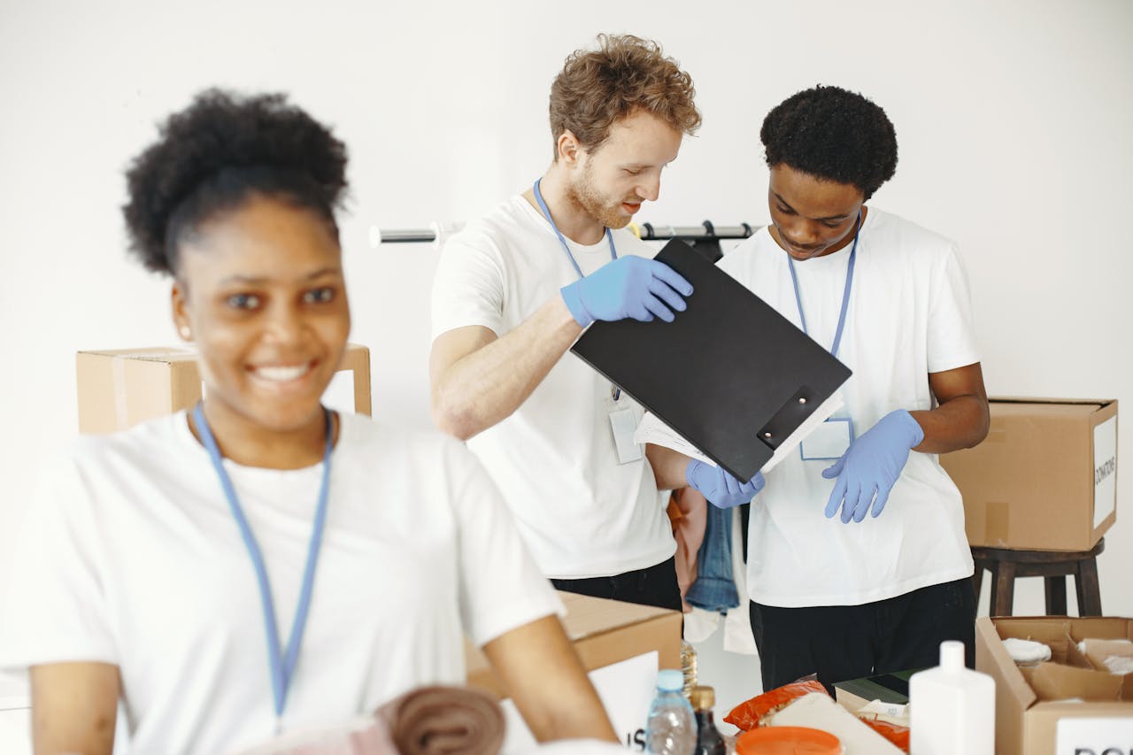 A diverse group of young volunteers organizing donations indoors with a cheerful atmosphere.